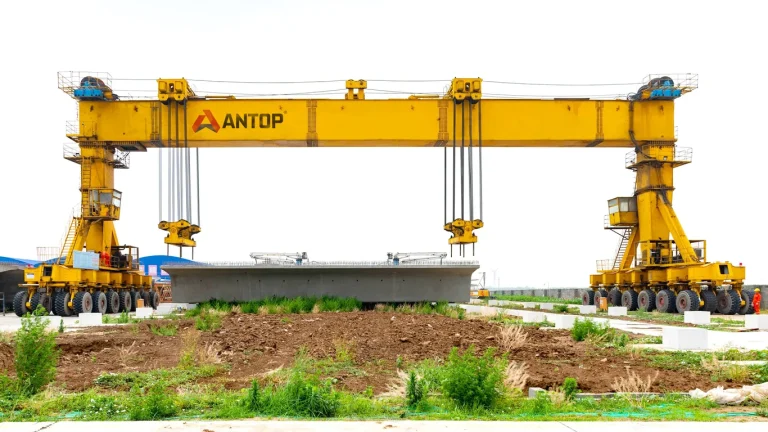 rubber tyred gantry crane lifting precast concrete beam in construction yard